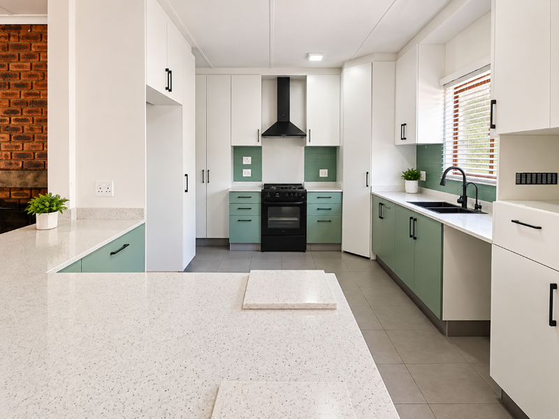 Modern kitchen featuring white and sage green cabinetry, quartz countertops, a gas hob, and a tiled backsplash with a clean, contemporary finish.