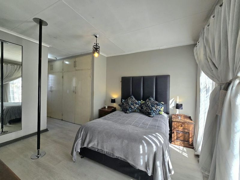 A bedroom featuring built-in cupboards, laminate flooring, and a ceiling-mounted light fixture.