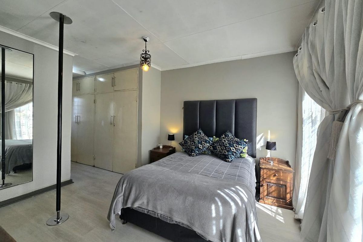 A bedroom featuring built-in cupboards, laminate flooring, and a ceiling-mounted light fixture.
