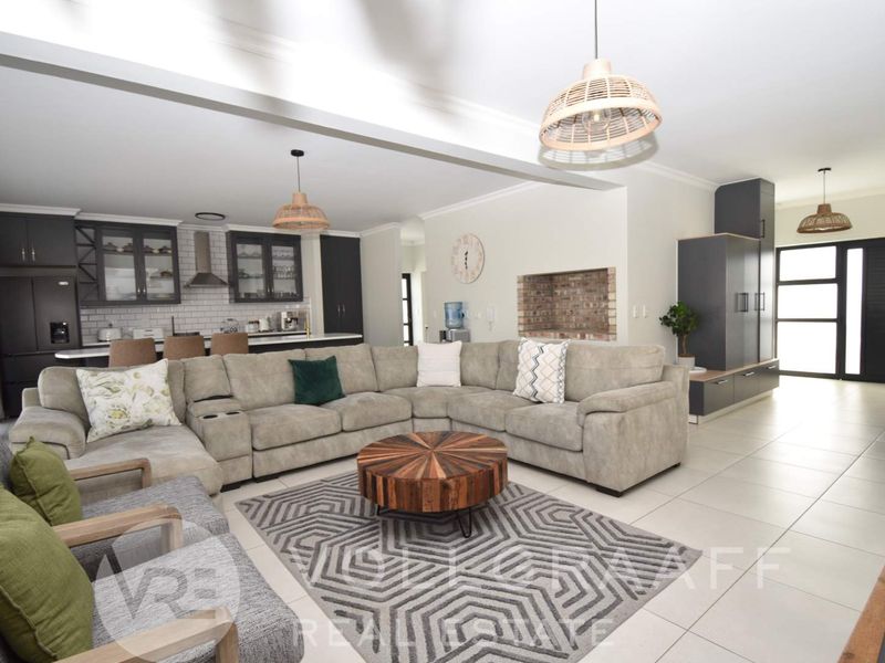 Spacious open-plan living area featuring a modern kitchen with subway tile backsplash, central island, and a cozy exposed brick fireplace feature.