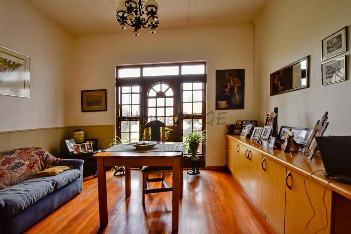 A living room featuring polished timber flooring, built-in cabinetry, and a classic timber-framed glass door leading to the exterior.