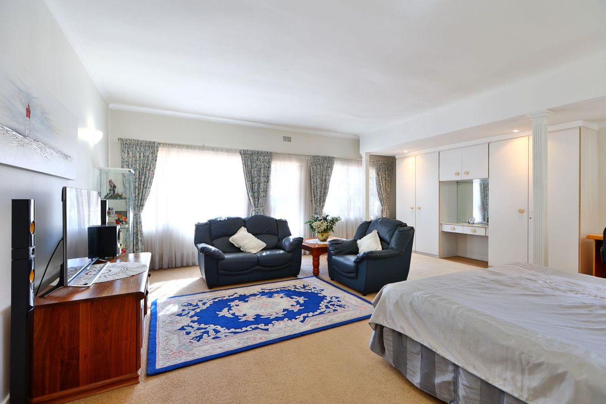 Spacious bedroom featuring built-in wardrobes with integrated vanity, neutral wall finishes, and large windows allowing for ample natural light.