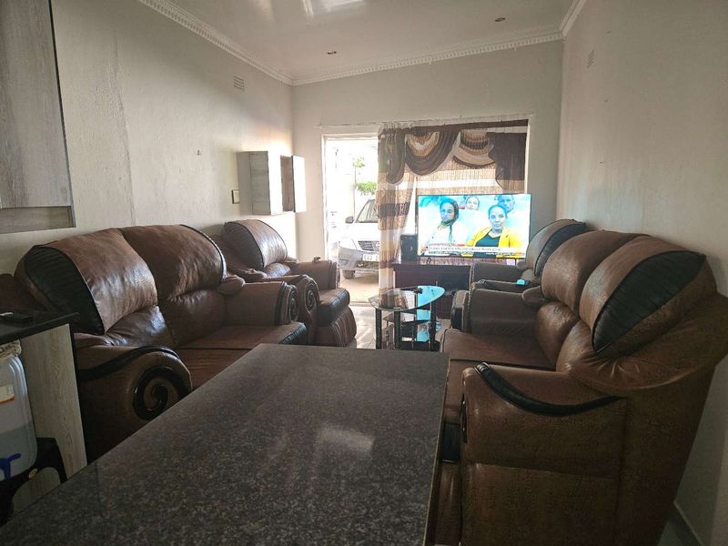 A living room area featuring decorative ceiling cornices and recessed lighting, currently furnished with a seating arrangement.