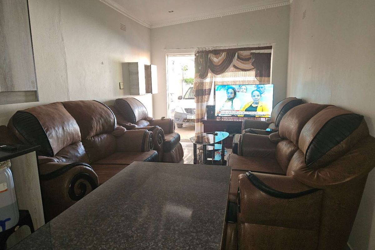 A living room area featuring decorative ceiling cornices and recessed lighting, currently furnished with a seating arrangement.