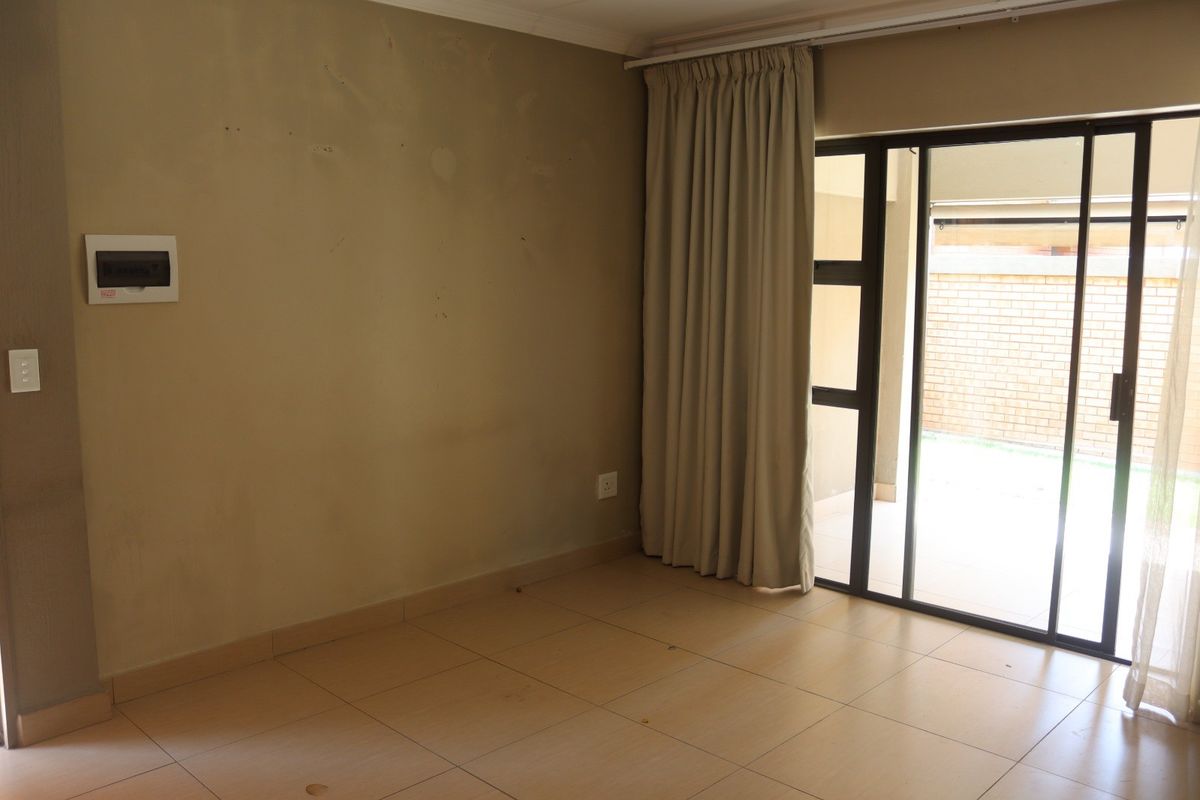 An empty living room featuring tiled flooring and a sliding glass door providing access to an outdoor area.
