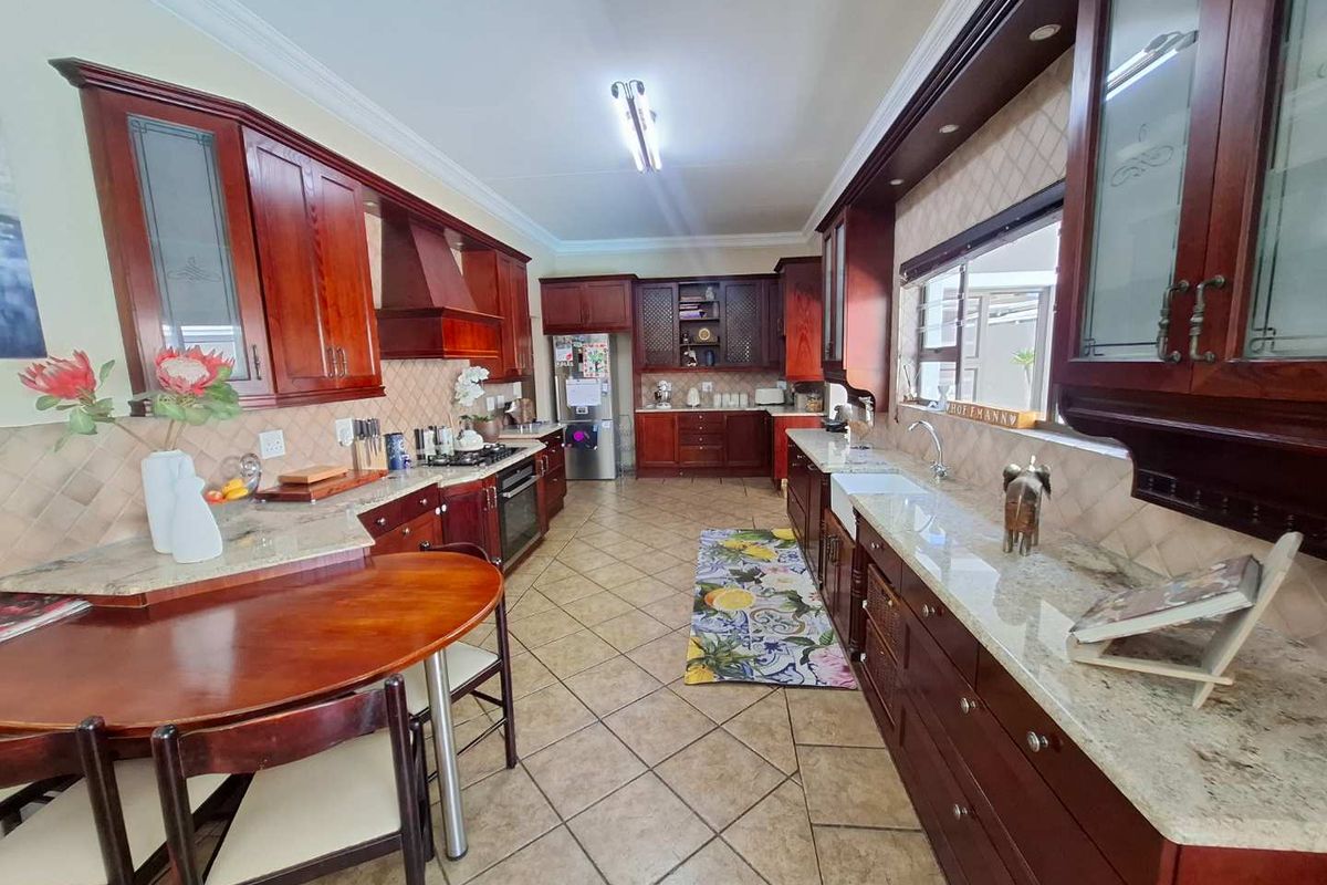 Spacious kitchen featuring rich wood cabinetry, granite countertops, a farmhouse sink, and a gas hob, offering a classic and functional culinary space.