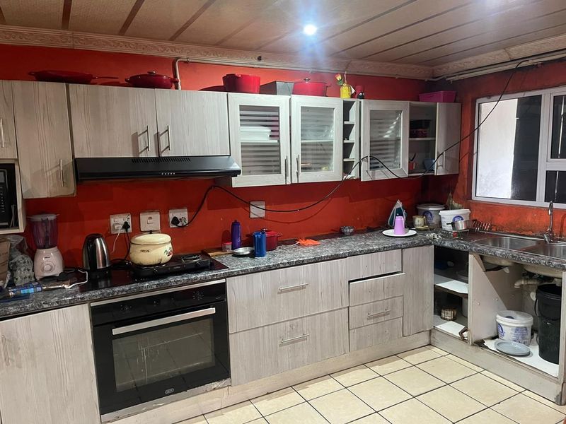 Kitchen featuring light wood-grain cabinetry, granite-look countertops, built-in oven, and extractor fan, requiring some maintenance and cosmetic updates.