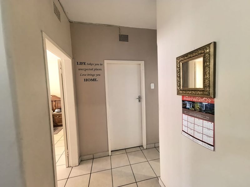 A functional hallway featuring tiled flooring and access to adjacent rooms, providing a clean and neutral transition space within the apartment.