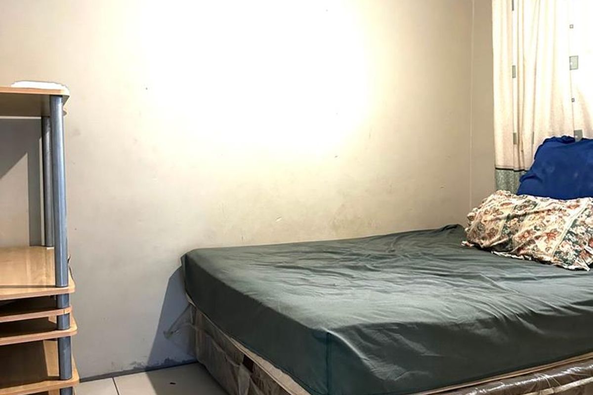 A bedroom featuring tiled flooring, crown molding, and a window with curtains.