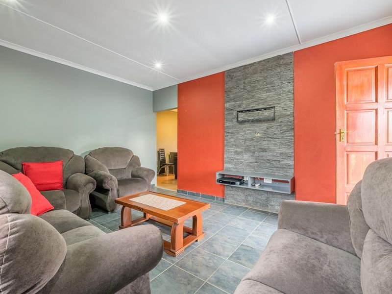 Living room featuring a stone-clad feature wall, tiled flooring, and recessed downlighting, providing a functional and defined space.
