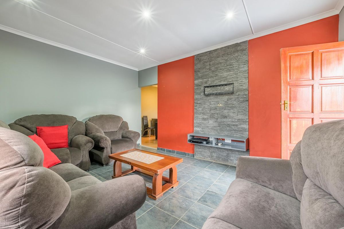 Living room featuring a stone-clad feature wall, tiled flooring, and recessed downlighting, providing a functional and defined space.