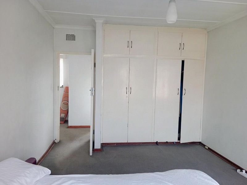 A bedroom featuring built-in cupboards with overhead storage and carpeted flooring, offering a functional space with potential for cosmetic updates.