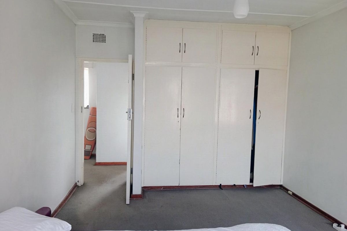 A bedroom featuring built-in cupboards with overhead storage and carpeted flooring, offering a functional space with potential for cosmetic updates.