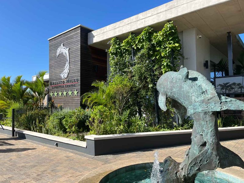 The entrance to the Ballito Hills Lifestyle Centre featuring a modern facade with timber cladding, a vertical garden, and a decorative water feature.