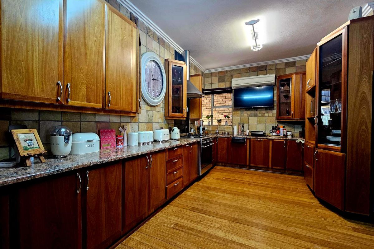 A traditional kitchen featuring wooden cabinetry, granite countertops, stone-tiled backsplash, and built-in oven with extractor fan.