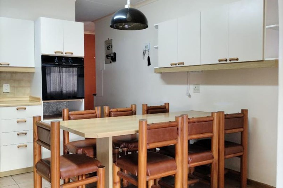 A functional kitchen and dining area featuring white cabinetry, built-in oven, and tiled flooring, offering a practical space for daily meals.