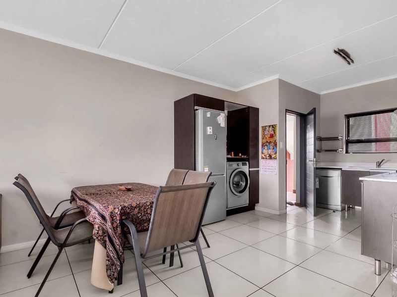 Open-plan living and kitchen area featuring tiled flooring, neutral walls, and integrated cabinetry with dedicated space for laundry appliances.
