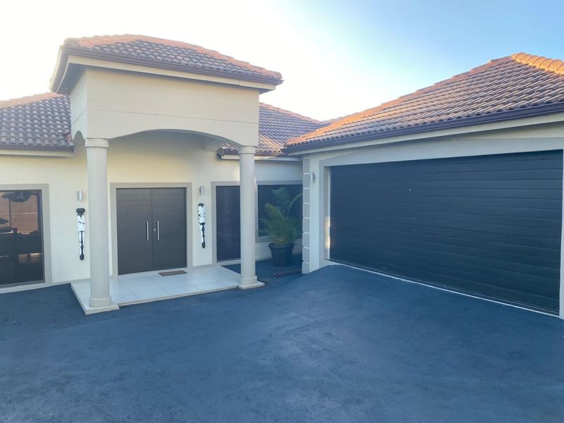 Front elevation of a modern house featuring a covered entrance porch with columns, a double garage, and a paved driveway.