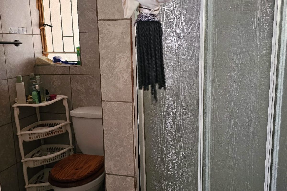 A functional bathroom featuring tiled walls, a standard toilet, and a shower enclosure with a textured glass door.