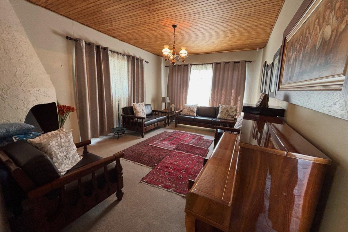A traditional living room featuring a warm timber-clad ceiling, carpeted flooring, and a built-in fireplace, offering a cozy and classic atmosphere.