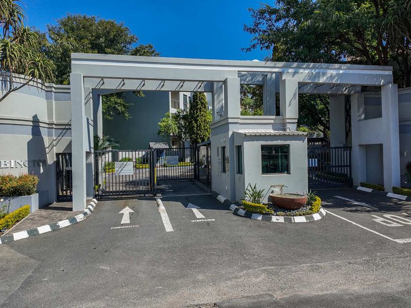 The main entrance to the Abbington apartment complex, featuring a secure gated access point, guard house, and well-maintained driveway.