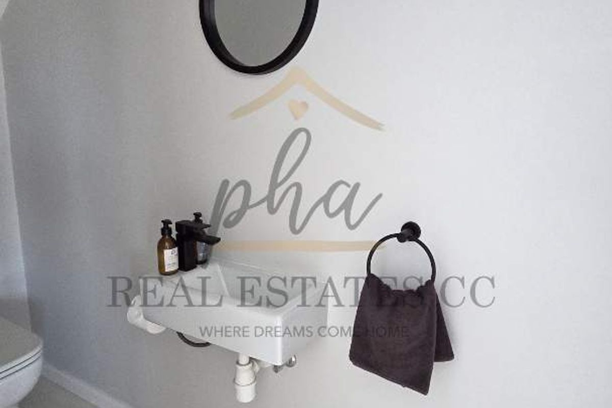 A compact guest bathroom featuring a wall-mounted basin, modern black fixtures, and a circular mirror.