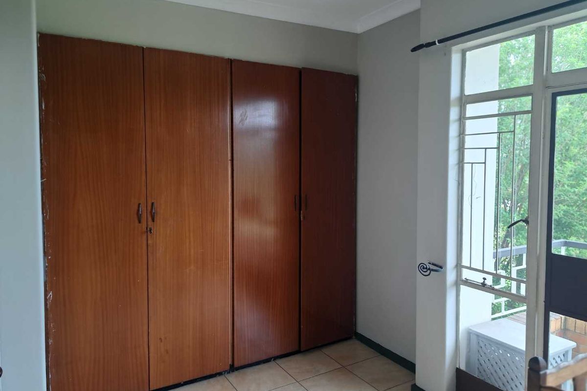 Bedroom featuring built-in wooden cupboards, tiled flooring, and direct access to an outdoor balcony area.
