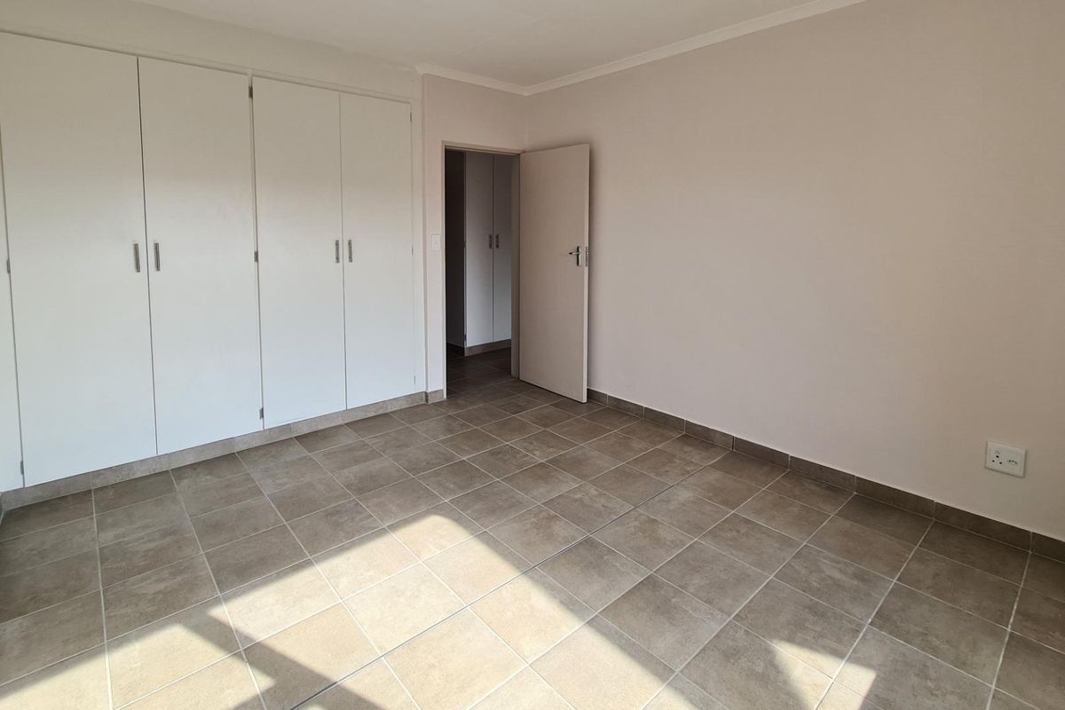 A clean, empty bedroom featuring neutral tiled flooring and ample built-in cupboard storage, providing a versatile space ready for personalization.