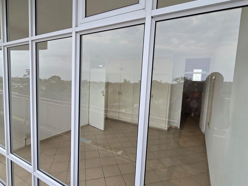 Enclosed balcony or sunroom featuring large aluminium-framed windows, tiled flooring, and built-in storage cupboards, offering a bright and versatile living space.