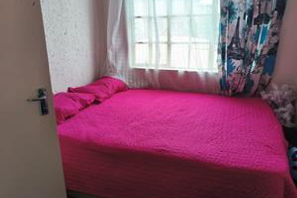 A compact bedroom featuring a window with natural light and standard door access.