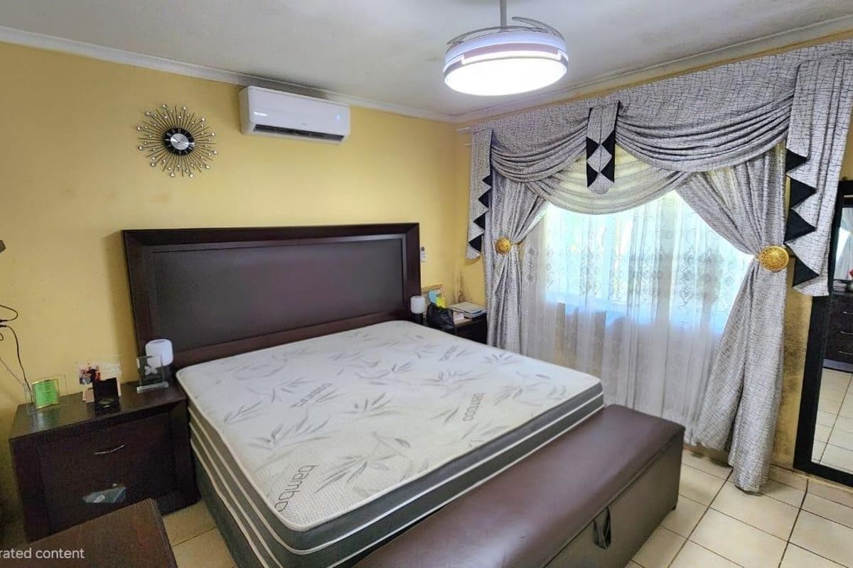 A bedroom featuring tiled flooring and a wall-mounted split-system air conditioner. The space requires cosmetic updates to the wall finishes.