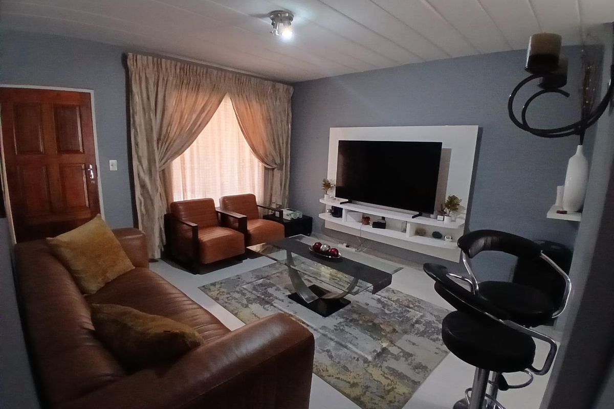 A comfortable living room featuring a built-in media console, tiled flooring, and a panelled ceiling, providing a functional space for relaxation.