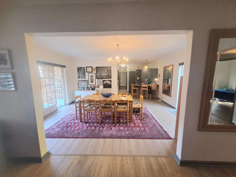 Spacious open-plan dining and kitchen area featuring laminate flooring, a central dining space, and direct access to an outdoor patio through glass doors.