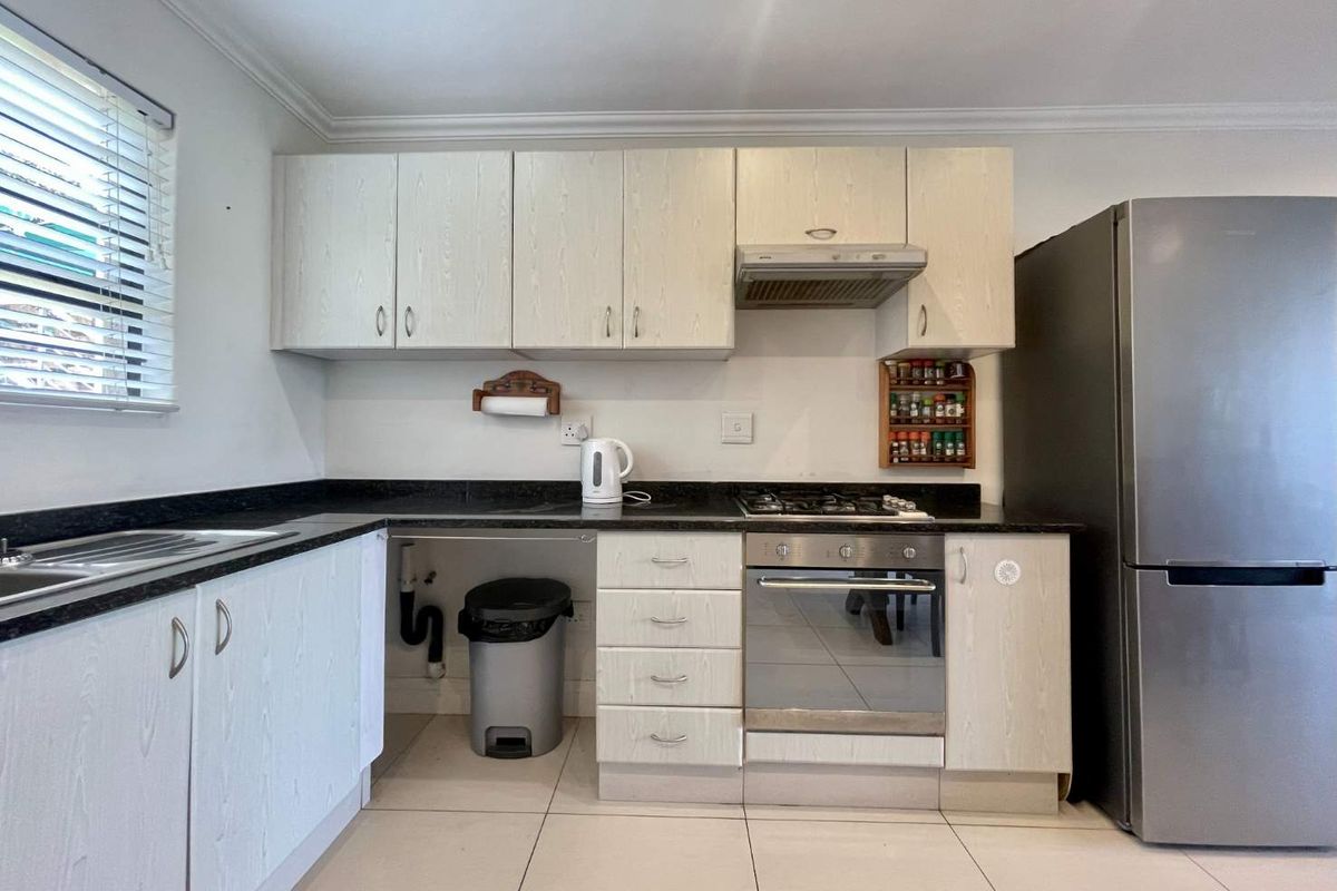 Functional kitchen featuring light-toned laminate cabinetry, granite countertops, built-in oven with gas hob, and tiled flooring.