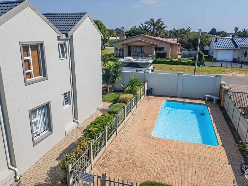 Aerial view of the property featuring a private swimming pool, paved patio area, and secure boundary walls within a residential setting.