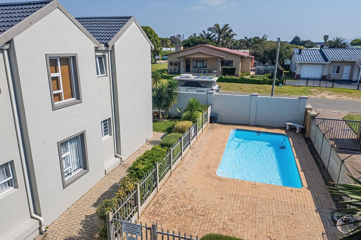Aerial view of the property featuring a private swimming pool, paved patio area, and secure boundary walls within a residential setting.