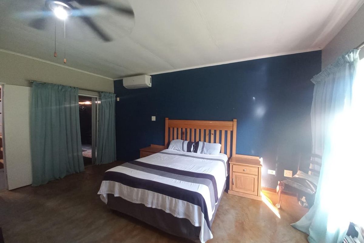 Spacious bedroom featuring polished concrete floors, a ceiling fan, and a wall-mounted split-system air conditioner with access to an outdoor area.