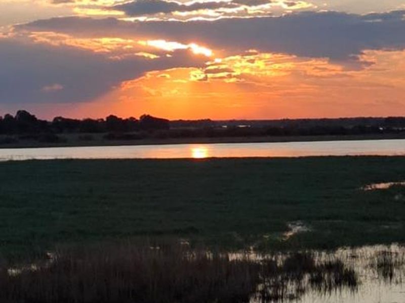 A scenic sunset view over the natural landscape and water, showcasing the tranquil outdoor environment surrounding the lodge.