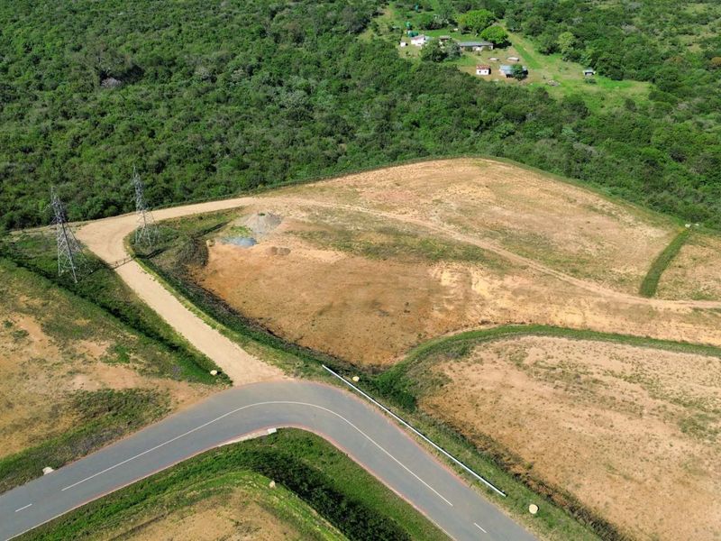 Aerial view of a large, undeveloped industrial land parcel featuring paved road access and high voltage power infrastructure.