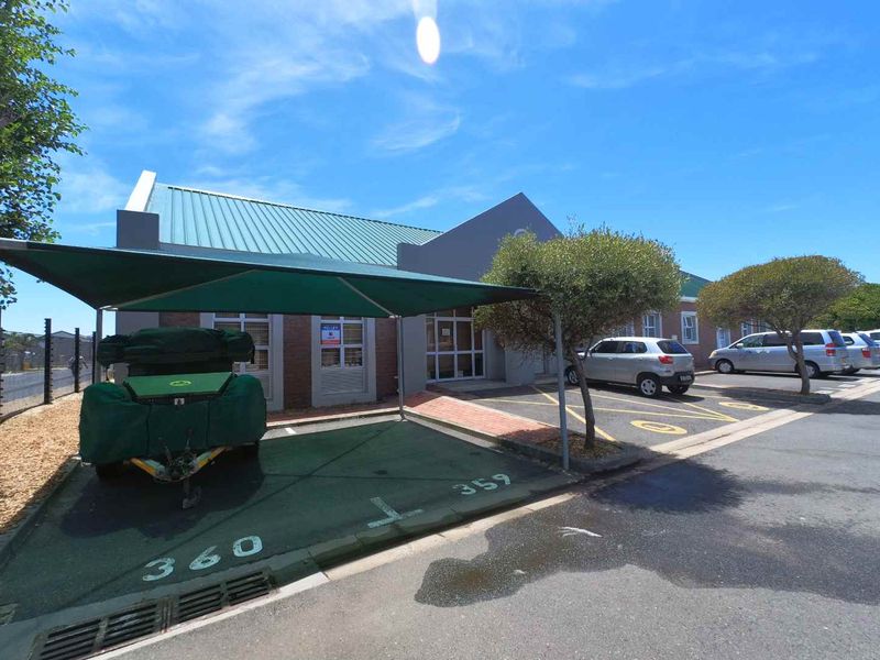 Front exterior view of the office building featuring dedicated shaded parking bays, brick facade, and metal roofing.