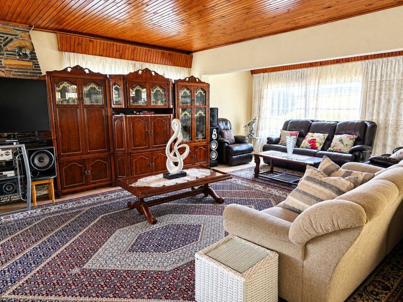 A spacious living room featuring a distinctive timber tongue and groove ceiling and a stone-clad fireplace surround, offering a warm and traditional aesthetic.