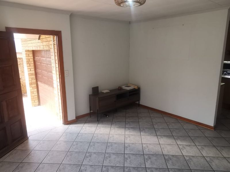 An open-plan living area featuring neutral tiled flooring and direct access to the exterior garage area.