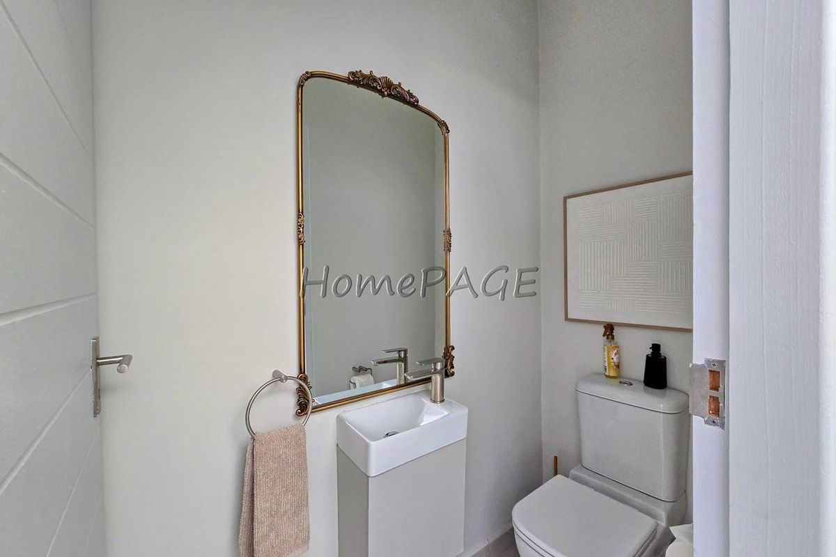 A compact guest bathroom featuring a wall-mounted vanity basin, modern mixer tap, and a standard toilet.