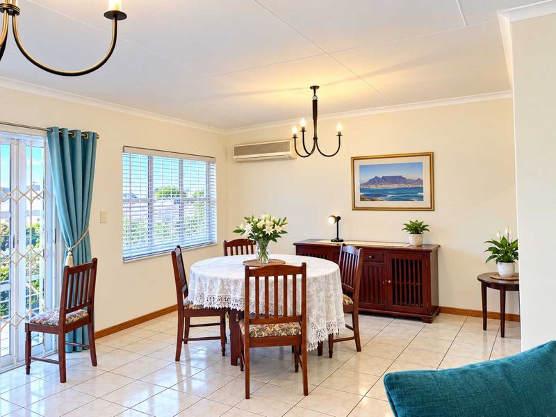 A bright and well-maintained dining area featuring tiled flooring, an air conditioning unit, and a sliding door leading to an outdoor space.