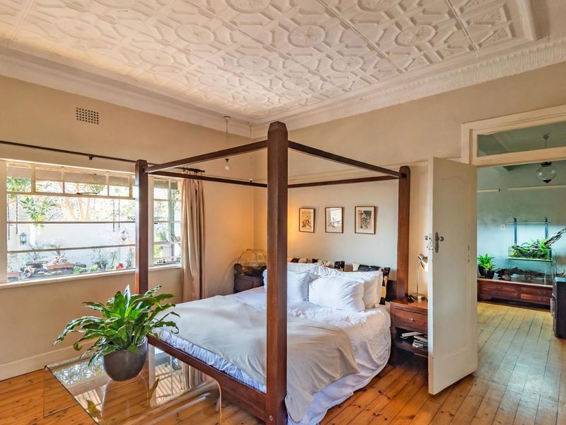 Spacious bedroom featuring a decorative pressed metal ceiling, polished timber flooring, and large casement windows allowing for natural light.