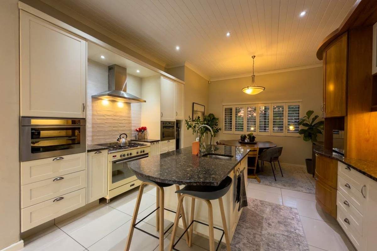 A well-appointed kitchen featuring a central island with a sink, built-in oven, gas hob, extractor fan, and ample cabinetry with granite countertops.