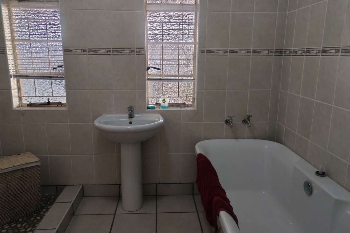 A functional bathroom featuring a pedestal basin, a standard bathtub, and tiled walls and flooring.