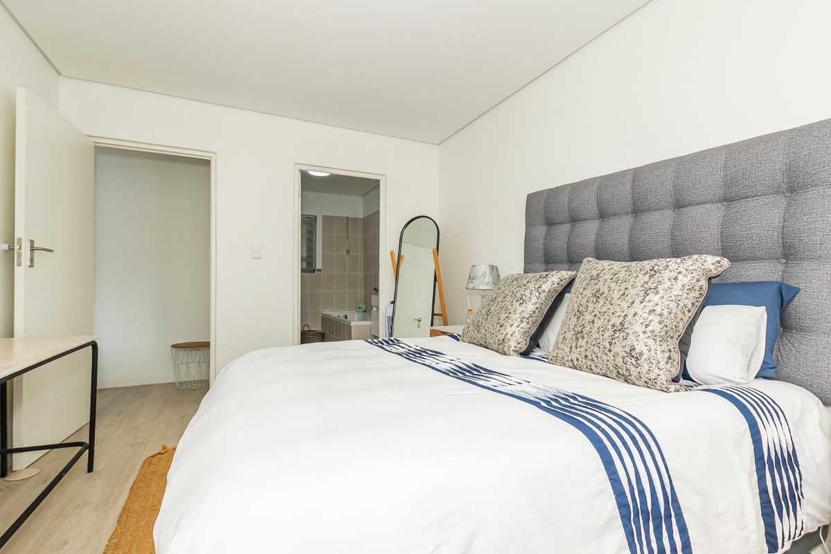 A well-maintained bedroom featuring neutral finishes, laminate flooring, and direct access to an en-suite bathroom.