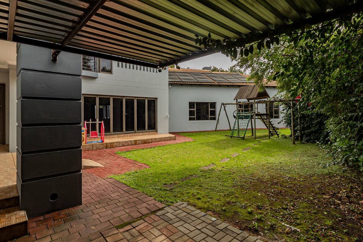 A spacious rear garden featuring a covered patio area, brick paving, and a lawn, providing a functional outdoor space for the home.