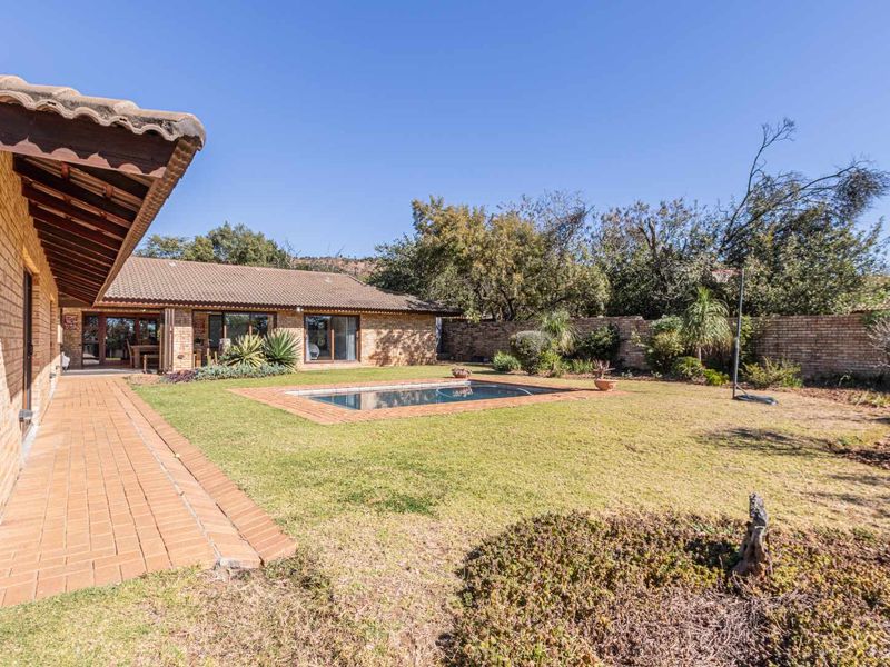 A spacious rear garden featuring a swimming pool, brick-paved walkway, and established boundary walls, offering a private outdoor living space.